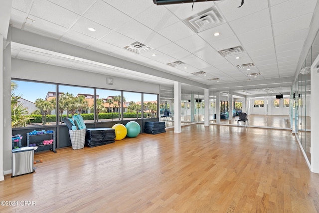 exercise area with a paneled ceiling, light hardwood / wood-style flooring, and french doors