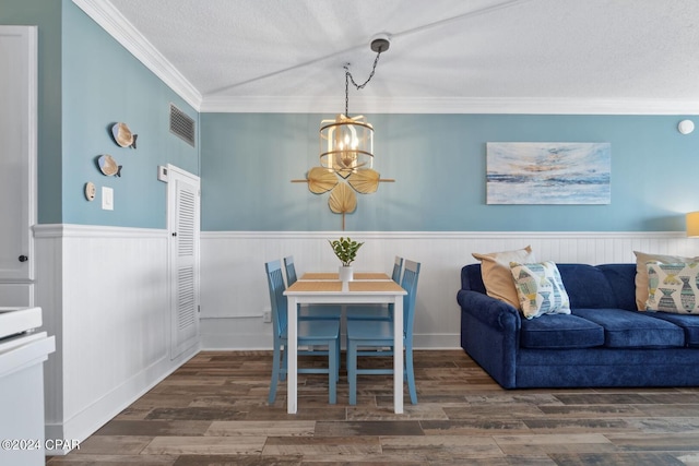 dining room featuring a notable chandelier, a textured ceiling, dark hardwood / wood-style floors, and ornamental molding