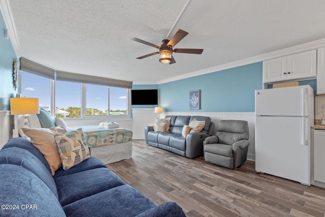 living room featuring ceiling fan, a textured ceiling, hardwood / wood-style floors, and ornamental molding