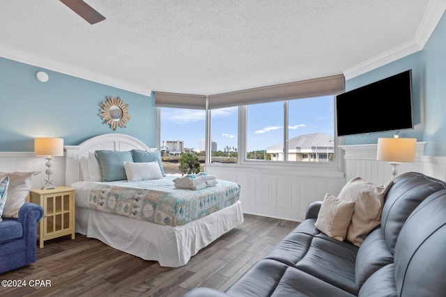 bedroom with a textured ceiling, wood-type flooring, crown molding, and ceiling fan