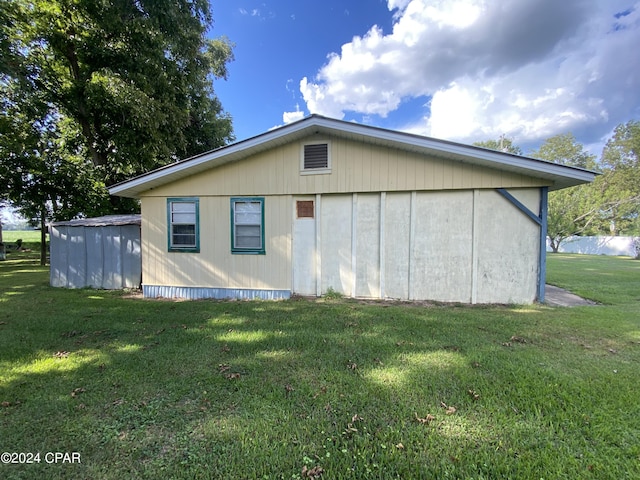 rear view of property with an outbuilding, a pole building, and a lawn