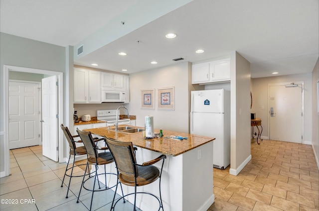 kitchen featuring white appliances, white cabinetry, a kitchen island with sink, and sink