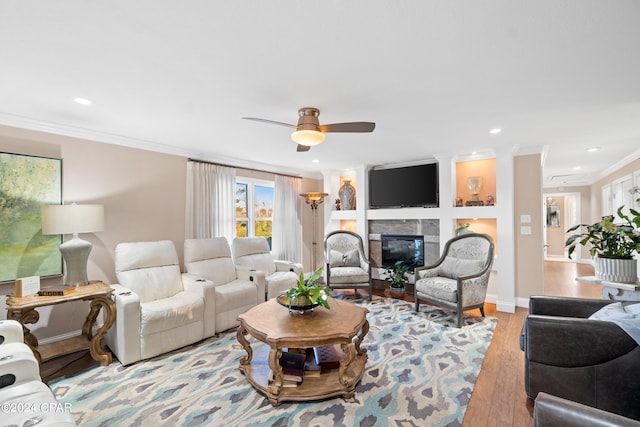 living room with ornamental molding, light wood-type flooring, a premium fireplace, and ceiling fan