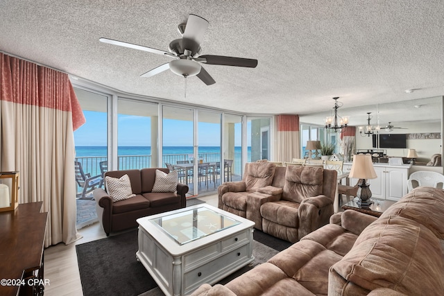 living room featuring a textured ceiling, ceiling fan with notable chandelier, hardwood / wood-style floors, and a water view