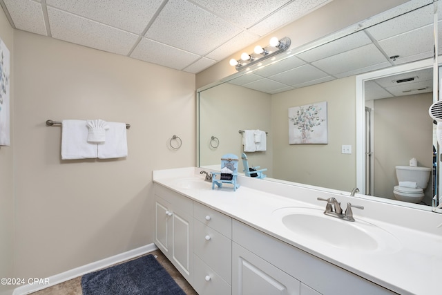 bathroom with a paneled ceiling, vanity, and toilet