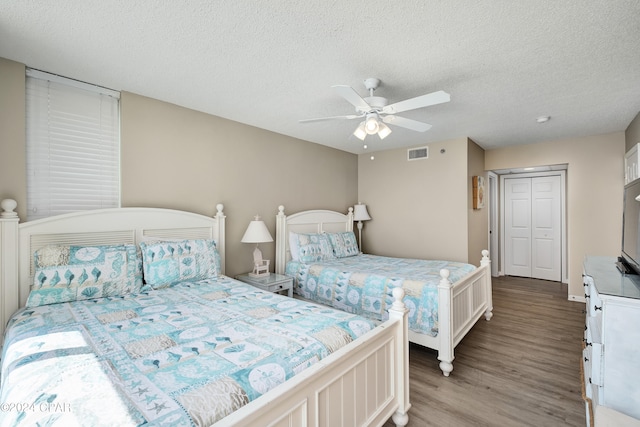 bedroom with a closet, ceiling fan, hardwood / wood-style floors, and a textured ceiling