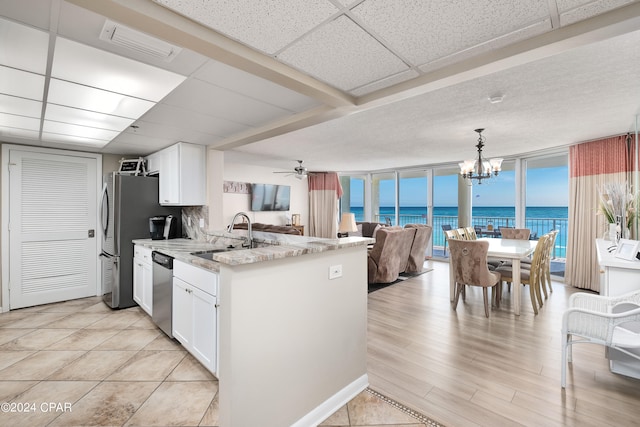 kitchen featuring hanging light fixtures, stainless steel dishwasher, sink, and white cabinets