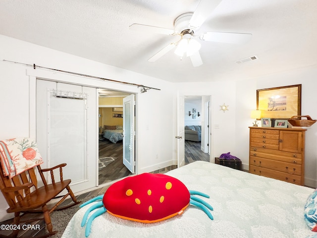 bedroom with a closet, ceiling fan, dark hardwood / wood-style floors, and a textured ceiling