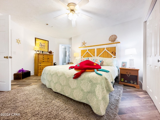 bedroom with a textured ceiling, wood-type flooring, ceiling fan, and a closet