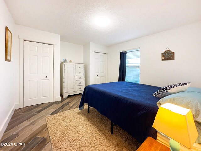 bedroom featuring a textured ceiling and dark hardwood / wood-style flooring