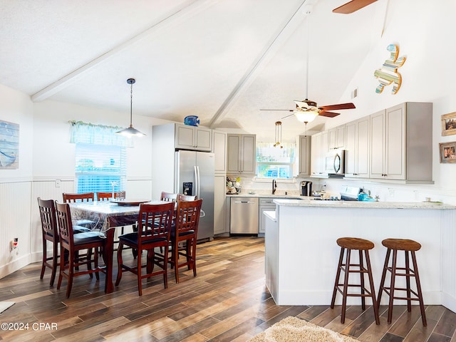 kitchen with light stone counters, ceiling fan, appliances with stainless steel finishes, and dark wood-type flooring