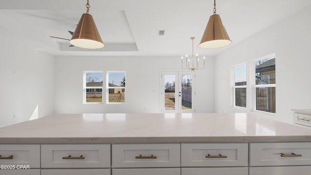 kitchen with hanging light fixtures and light stone countertops