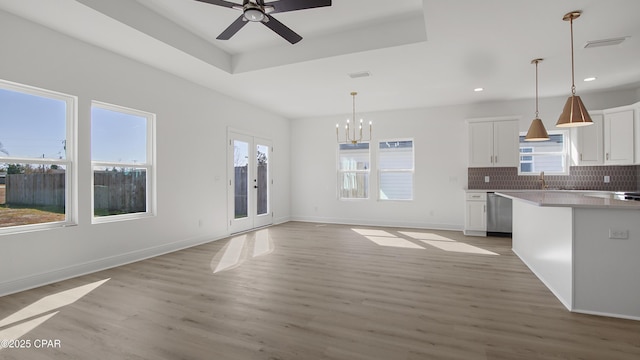 kitchen featuring hanging light fixtures, stainless steel dishwasher, white cabinets, and a tray ceiling