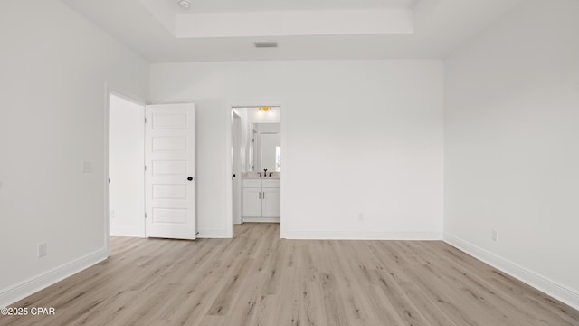 unfurnished room featuring a tray ceiling and light hardwood / wood-style floors