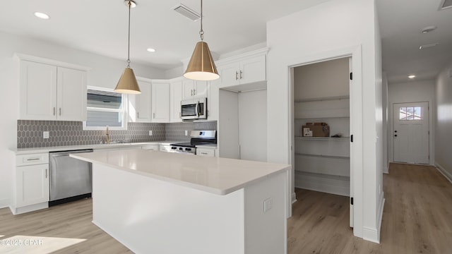 kitchen featuring white cabinetry, sink, hanging light fixtures, a center island, and stainless steel appliances