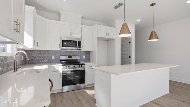 kitchen with stainless steel appliances, a kitchen island, sink, and white cabinets