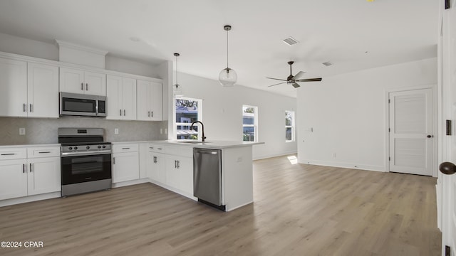 kitchen with appliances with stainless steel finishes, white cabinetry, a peninsula, and tasteful backsplash