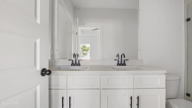 full bathroom featuring toilet, double vanity, and a sink