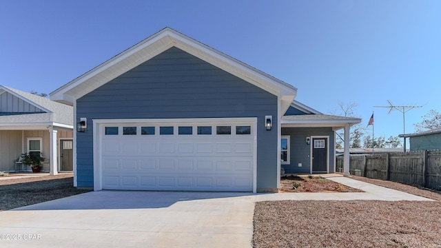 view of front of property featuring a garage, concrete driveway, and fence