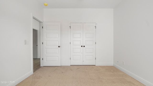 unfurnished bedroom with light carpet and a closet