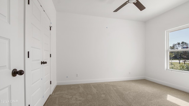 carpeted empty room featuring ceiling fan and baseboards