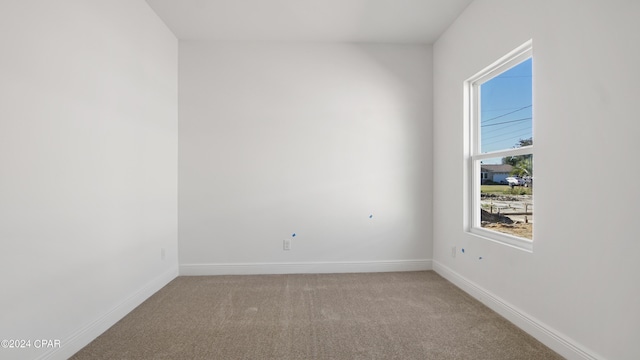 spare room with light carpet and baseboards