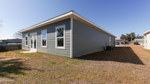 view of side of home with a yard, french doors, and cooling unit