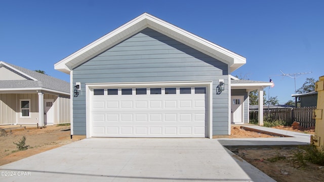 garage featuring concrete driveway and fence