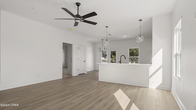 unfurnished living room with light wood-style floors, ceiling fan, baseboards, and a sink