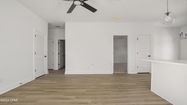 unfurnished room featuring light wood-style floors, visible vents, baseboards, and a ceiling fan