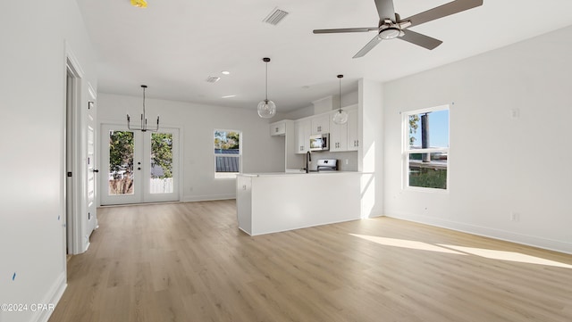 kitchen with white cabinets, hanging light fixtures, light hardwood / wood-style floors, and a wealth of natural light