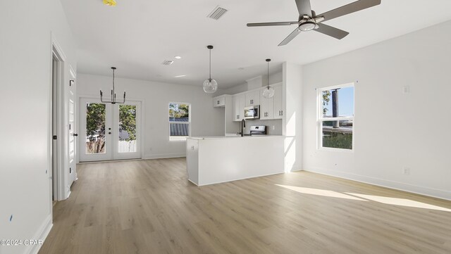 kitchen with stainless steel appliances, white cabinets, sink, light hardwood / wood-style floors, and decorative light fixtures