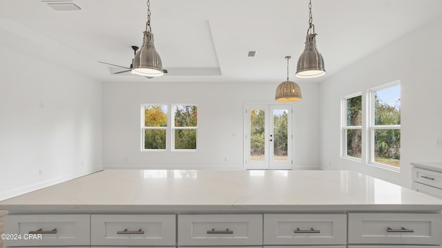 kitchen featuring a wealth of natural light, ceiling fan, light stone countertops, and decorative light fixtures