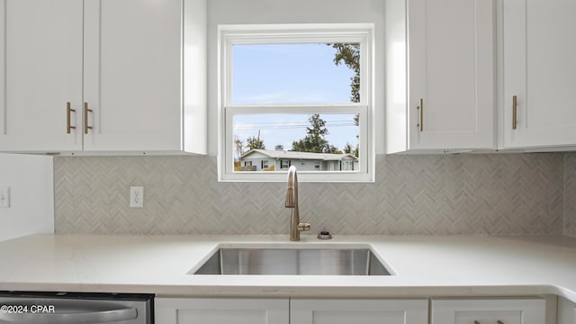 kitchen featuring stainless steel dishwasher, white cabinetry, sink, and tasteful backsplash