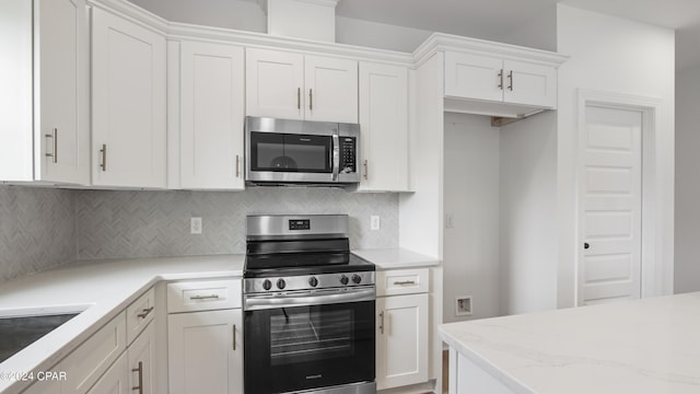 kitchen with white cabinets, light stone countertops, stainless steel appliances, and tasteful backsplash