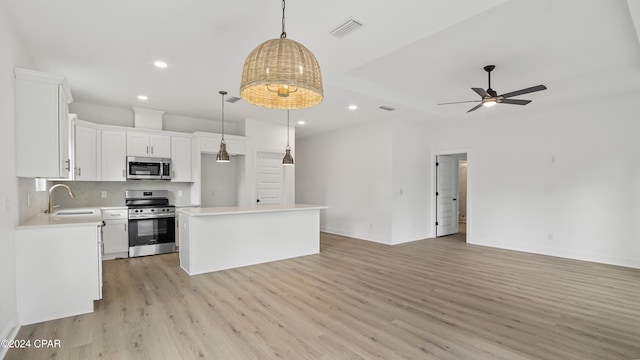 kitchen with a center island, white cabinets, stainless steel appliances, and decorative light fixtures