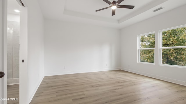 unfurnished room with a tray ceiling, ceiling fan, and light hardwood / wood-style floors