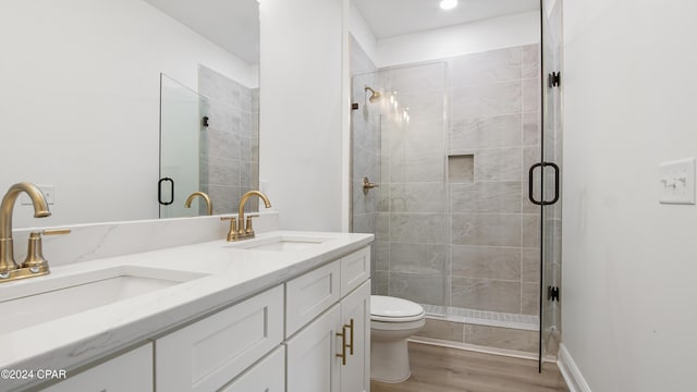 bathroom featuring a shower with door, vanity, wood-type flooring, and toilet