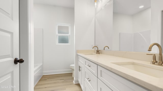 full bathroom with wood-type flooring, vanity, shower / bath combination, and toilet