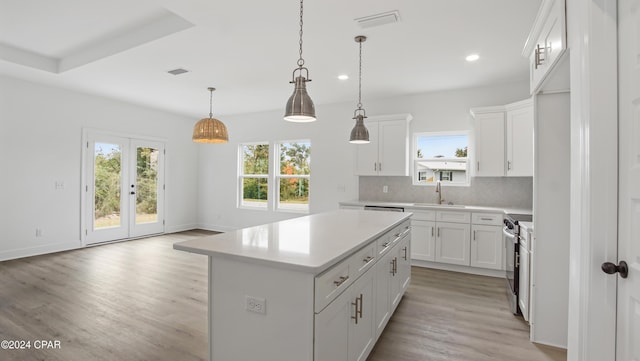 kitchen featuring pendant lighting, a center island, white cabinetry, and stainless steel electric range