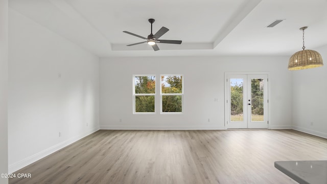 unfurnished room featuring french doors, light hardwood / wood-style floors, ceiling fan, and a tray ceiling