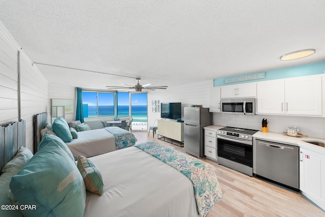 interior space featuring stainless steel fridge, ceiling fan, light hardwood / wood-style floors, and a textured ceiling