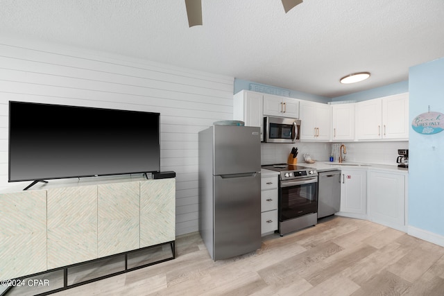 kitchen with a textured ceiling, appliances with stainless steel finishes, sink, light wood-type flooring, and white cabinets