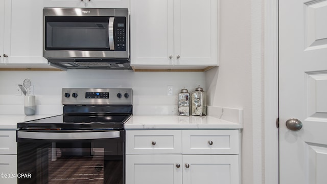 kitchen featuring light stone counters, white cabinets, and stainless steel appliances