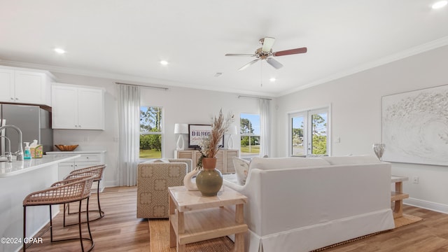 living room with ceiling fan, light hardwood / wood-style floors, and ornamental molding