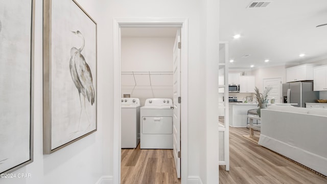 laundry room with washer and dryer, light wood-type flooring, and ornamental molding