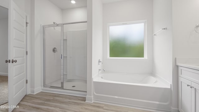 bathroom with hardwood / wood-style floors, vanity, and shower with separate bathtub