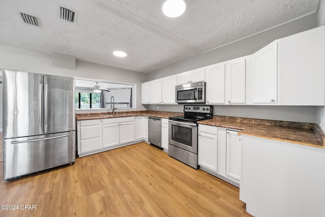 kitchen with appliances with stainless steel finishes, light hardwood / wood-style floors, white cabinetry, ceiling fan, and sink