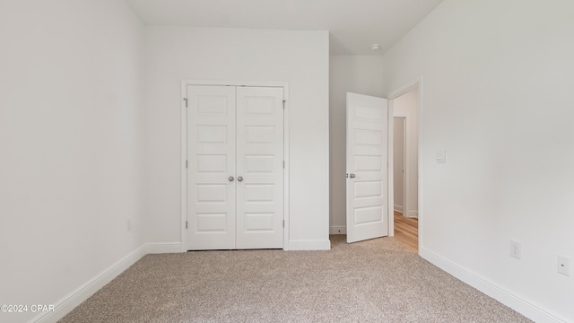 unfurnished bedroom with a closet and light carpet