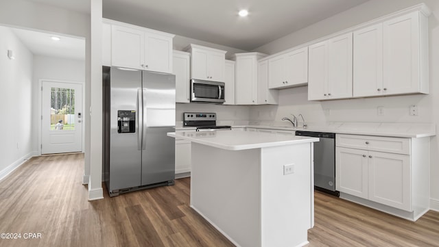 kitchen with stainless steel appliances, dark wood-type flooring, a center island, sink, and white cabinetry